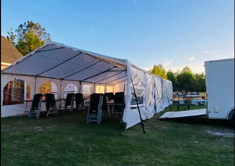 White tent set up on grass at golden hour with chairs inside